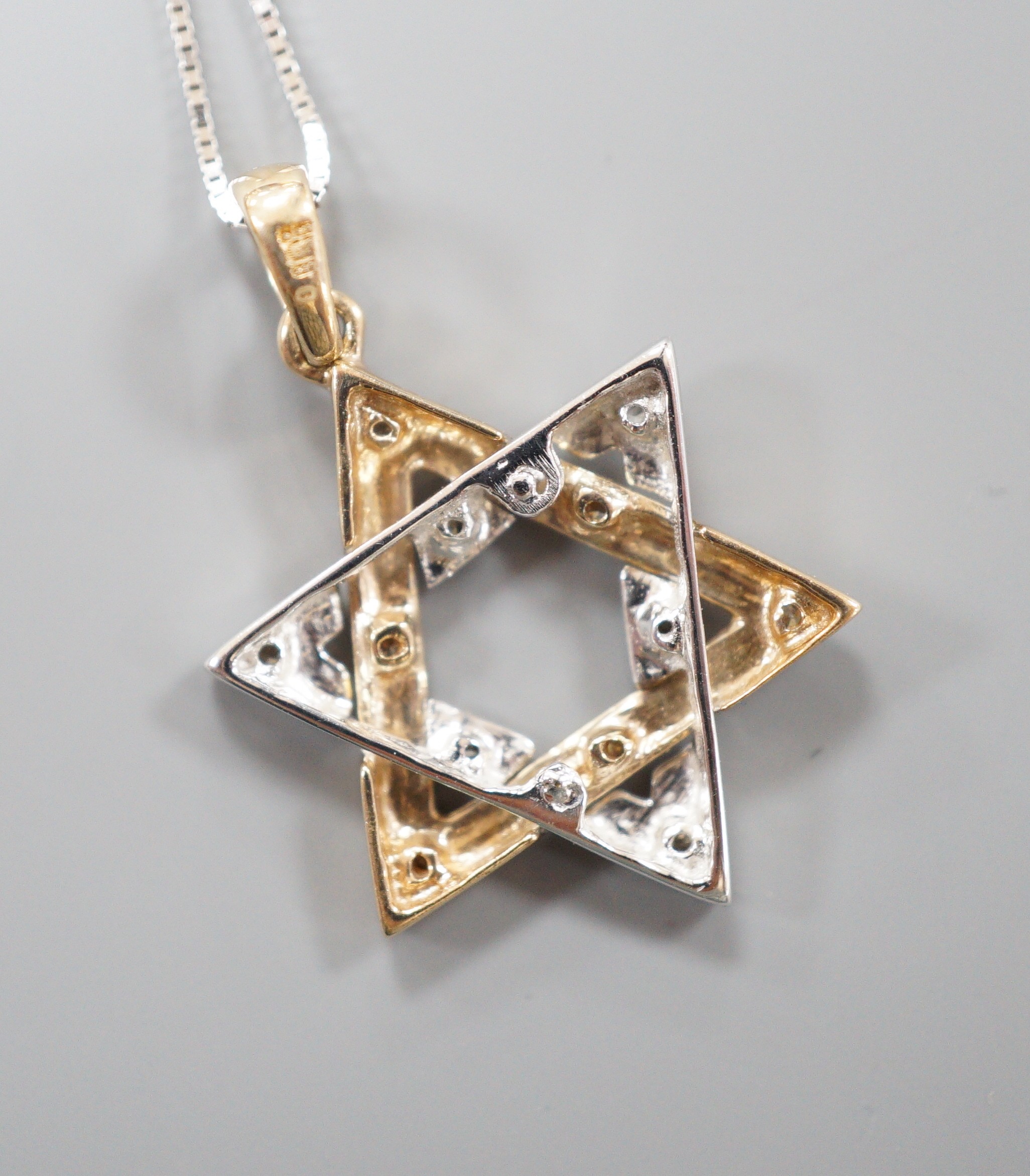 A modern two colour 9ct gold and diamond chip set 'Star of David' pendant, overall 25mm, on a 375 white metal fine link chain, 40cm, gross weight 2.8 grams.